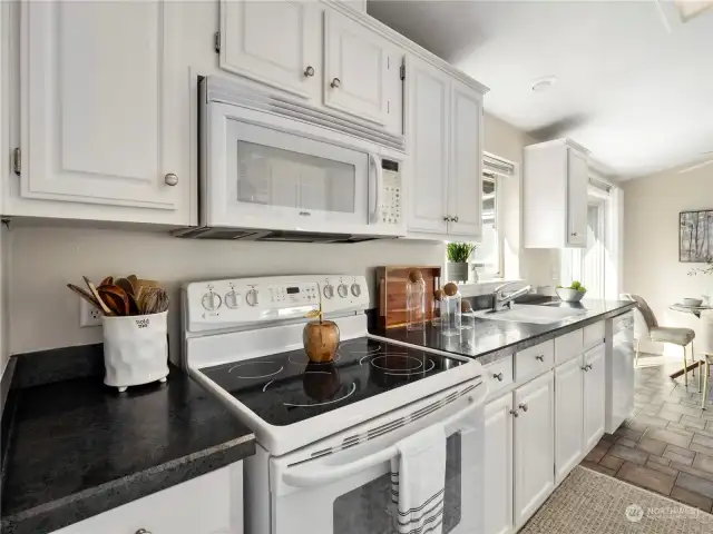 White cabinets with white appliances gives this kitchen a fresh, classic, and airy look and feel. Ample counterspace allows for more than one cook to work at the same time while entertaining guest at the same time.