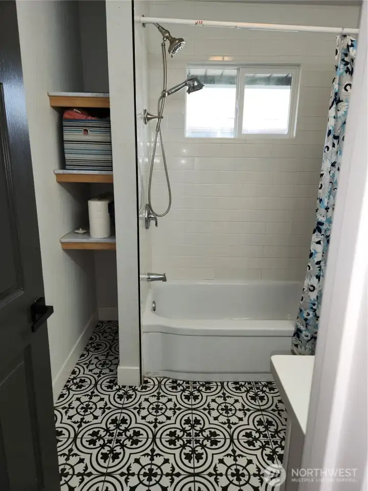 Storage space to the left of the tub/shower unit.