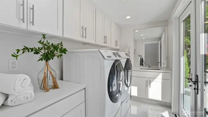Laundry room includes built-in cabinet storage, a utility sink, and extra counter space.