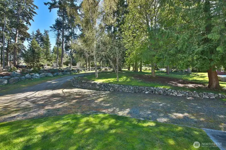 Your back is to the front of the house and you are looking back towards Rhodena Drive. The treed yard provides a privacy buffer between the road and the home. Plenty of space for additional parking.