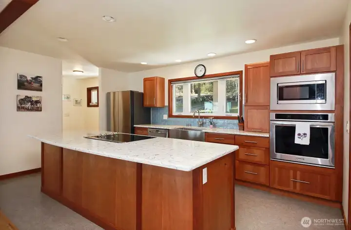 Open & spacious kitchen design with custom cherry cabinets & quartz countertops. To the left of the fridge is the other entry, closer to the garage. A WALK IN PANTRY is located at this entry as is the entrance to the garage.
