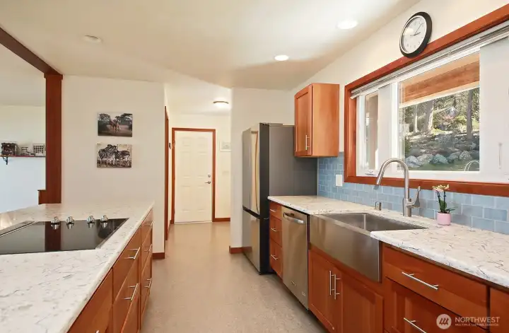 Looking through the kitchen to the other entryway. Straight ahead is the door to the garage (with a few steps down). Along the left side of this entryway is a walk in pantry with a pocket door. There is a bench and space to hang jackets in this entryway.