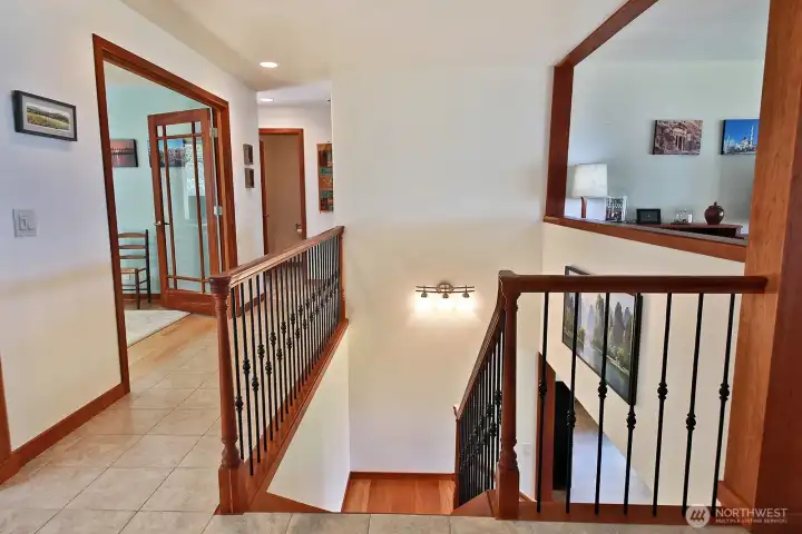 Glass doors open to the office, you can see the half bath at the end of the hallway. Laundry to the left & Primary to the right. This staircase was rebuilt during the remodel with Brazilian Cherry wood.
