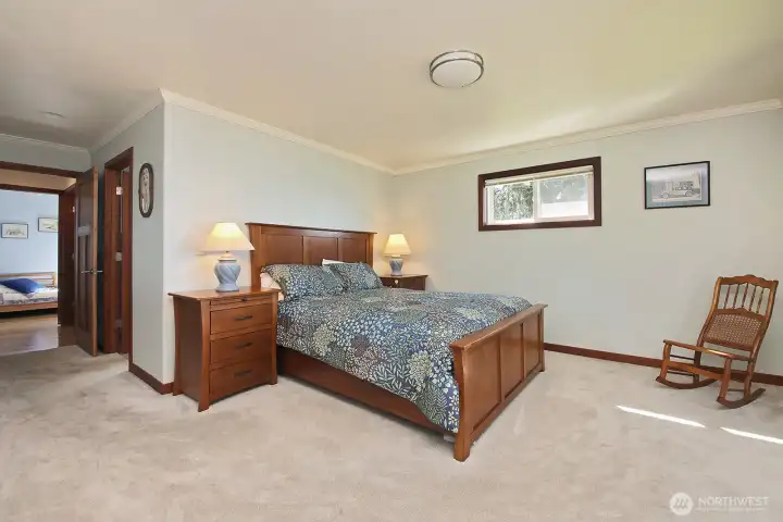Spacious Primary Bedroom. Door to the Primary Bath is to the right and you can glimpse the laundry room across the hall. Double closets are across from the bathroom door (just beyond the left edge of this photo).