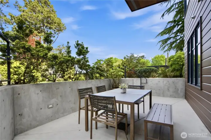 A sheltered, private al fresco dining terrace on the lower level — your own quiet garden room, enclosed and lush.