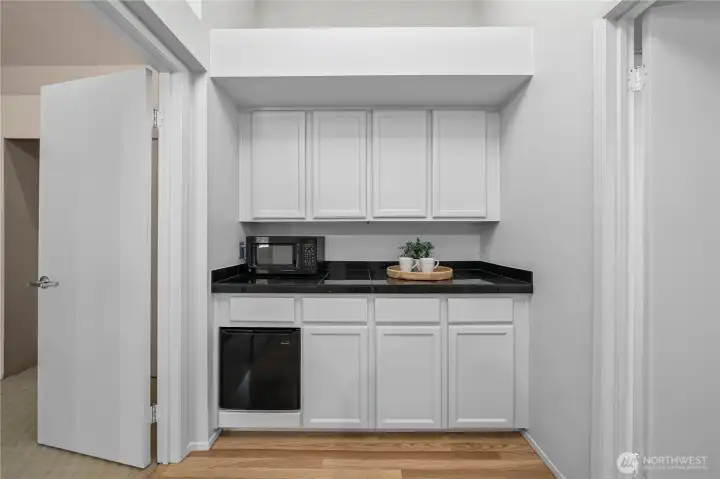 A thoughtfully designed upstairs beverage center with built-in cabinetry, countertop workspace, and a mini refrigerator provides the perfect spot for a morning coffee station, evening refreshments