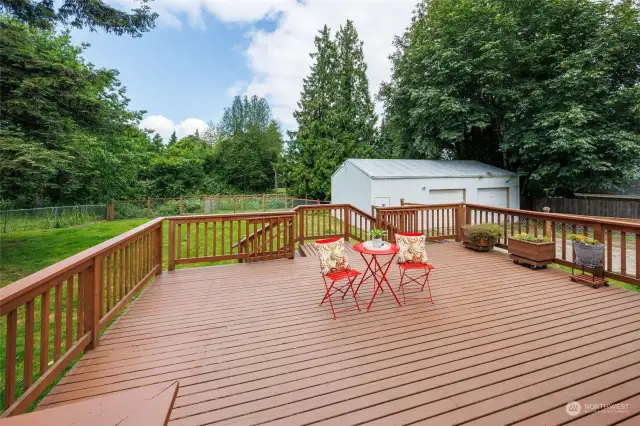 Spacious wood deck w/ stairs leading down to yard