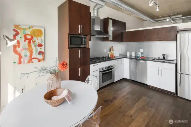 Floor-to-ceiling windows flood the space with natural light, highlighting the modern kitchen’s crisp white cabinetry and polished countertops. Perfect for culinary creativity in a stylish urban setting.