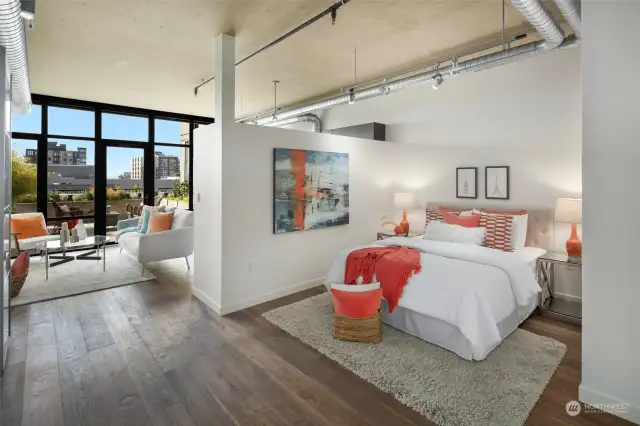 This airy bedroom with exposed industrial ceilings and modern design elements opens up to the living area, creating a peaceful space.