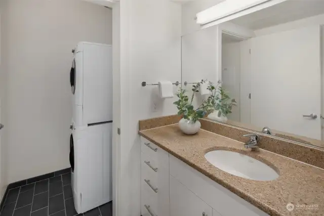 A full-size, stacked washer and dryer set is conveniently tucked away in a separate laundry area just off the bathroom, making laundry tasks both accessible and discreet.