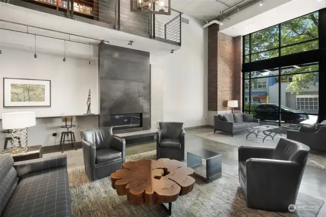 Relax in the beautifully designed lobby / lounge area featuring a stunning fireplace, modern furnishings, and high ceilings with an industrial loft aesthetic