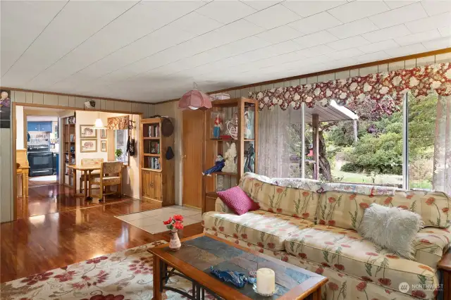 Living room has a large window. The breakfast nook is ahead to the right with the kitchen beyond.