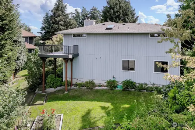 The neat backyard has mature plants and beautiful flower beds.