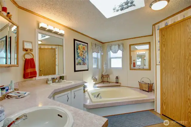 Bathroom off the main bedroom with oversized sunken tub and double sinks. Door to the right is storage closet and where the water heater is located.