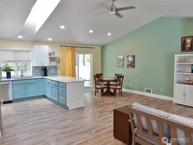 Open Great Room w design w/ vaulted ceiling and ceiling fan.