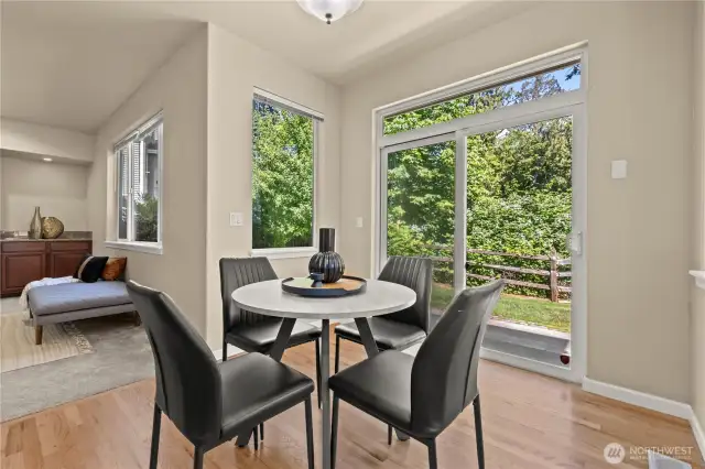 Enjoy peaceful greenbelt views from this sunny breakfast nook, located just off the kitchen and secondary living room in this well-appointed Puyallup, WA home. Surrounded by windows on two sides and a large sliding glass door that leads to the backyard, this space is perfect for casual dining or morning coffee with a view. Natural light pours in from the fully fenced backyard and wooded greenbelt, creating a tranquil atmosphere in the heart of the LaGrande Station community. With hardwood floors and easy flow into the main living spaces, this nook is both stylish and functional.
