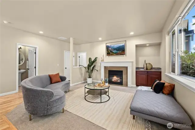 This cozy secondary living room in Puyallup’s LaGrande Station community blends warmth, style, and smart layout. The elegant gas fireplace anchors the space, while large windows bring in light and greenbelt views. This angle showcases direct access to the main-level half bath and nearby second primary suite, ideal for multigenerational living or guest privacy. Neutral tones, plush carpet, and built-in cabinetry make this room perfect for relaxing or entertaining in one of Puyallup, WA’s most desirable neighborhoods.