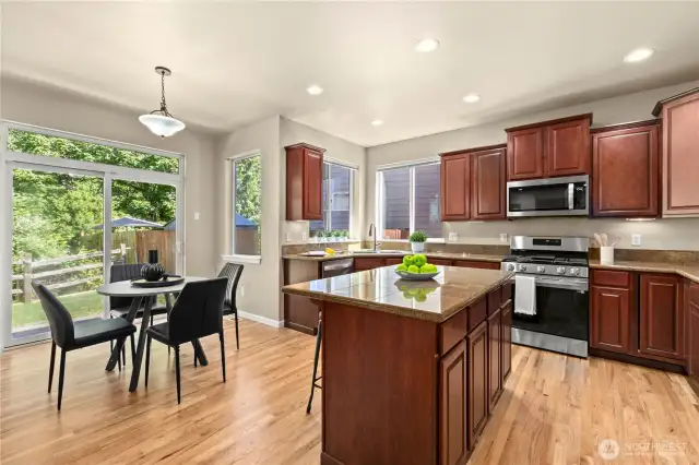 Located in the heart of Puyallup’s LaGrande Station community, this beautifully appointed kitchen features warm hardwood floors, granite countertops, rich cabinetry, and a center island with bar seating. Stainless steel appliances and a gas range add modern functionality, while large windows and a sliding glass door offer abundant natural light and scenic greenbelt views. The adjacent breakfast nook is ideal for casual meals, making this space the perfect balance of comfort, style, and practicality in one of Puyallup, WA’s most desirable neighborhoods.