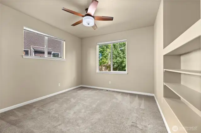 Spacious secondary primary bedroom with greenbelt views in Puyallup, WA    This light-filled secondary primary bedroom in Puyallup’s LaGrande Station community offers peaceful privacy and beautiful greenbelt views right from your window. Perfect for multigenerational living or flexible guest accommodations, this room features plush carpeting, a ceiling fan, built-in shelving, and dual windows that bring in natural light from both the side yard and the lush greenery beyond. Whether used as a second suite, home office, or private retreat, this versatile space adds exceptional livability to an already well-designed home in one of Puyallup, WA’s most desirable neighborhoods.