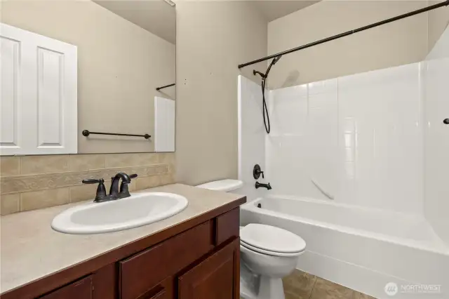 This private en-suite bathroom serves the secondary primary bedroom in the sought-after LaGrande Station community of Puyallup, WA. Featuring a clean, classic design, this full bath includes a shower/tub combo with updated oil-rubbed bronze fixtures, a single-sink vanity with rich wood cabinetry, and neutral tile flooring. Perfect for guests, multigenerational living, or extended stays, this bathroom provides privacy, comfort, and functionality in one of Puyallup’s most desirable neighborhoods.
