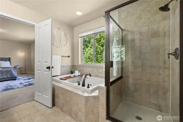Soaking tub with a view in the luxurious primary suite – Puyallup, WA real estate    Unwind in style with a relaxing soak in the deep jetted tub while enjoying peaceful greenbelt views right from your window. This primary ensuite bathroom in the heart of Puyallup’s LaGrande Station community also features a glass-enclosed walk-in shower, stylish bronze fixtures, and tile finishes that add elegance and comfort to your daily routine.