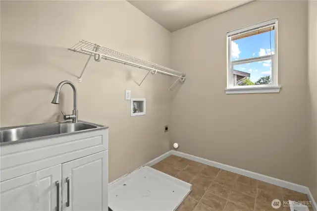 This functional and light-filled laundry room in Puyallup’s LaGrande Station community offers everything you need for efficient daily living. Featuring a built-in utility sink, upper wall-mounted shelf, and designated hookups for washer and dryer, this space is designed for convenience. A side-facing window provides natural light, while tile flooring ensures easy maintenance. Whether you’re managing daily laundry or cleaning up after outdoor activities, this dedicated utility space delivers practical comfort in one of Puyallup, WA’s most desirable neighborhoods.