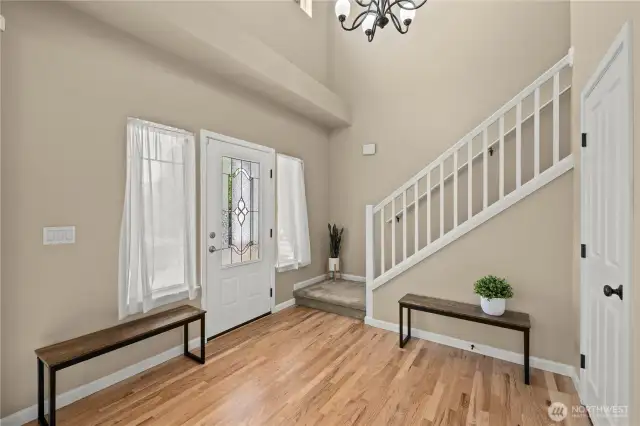Step into this bright and airy two-story foyer located in the heart of Puyallup’s LaGrande Station community. The entryway features beautifully maintained hardwood floors, a stylish frosted glass front door, and tall ceilings that add a grand, open feel. Flanked by twin side windows with sheer curtains, the space is filled with soft natural light. A modern chandelier and crisp white staircase provide a warm welcome and classic charm. Perfectly situated near schools, shopping, parks, and transit, this elegant entry sets the tone for comfortable, connected living in one of Puyallup, WA’s most desirable neighborhoods.