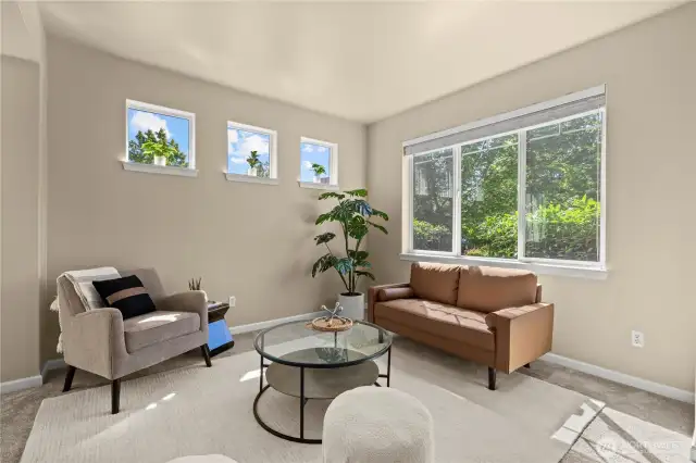 This welcoming front sitting room is filled with natural light from a large picture window overlooking Chateau Dr. Three additional upper accent windows add architectural character and brighten the space. Neutral paint tones, plush carpeting, and contemporary staging—including a tan leather loveseat, modern armchair, and round glass coffee table—create a cozy yet elegant space perfect for relaxing or greeting guests. Located at the front of the home, this room sets the tone for comfort and curb appeal.