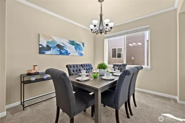 This elegant formal dining room in Puyallup, WA’s LaGrande Station community is the perfect space for hosting dinner parties or everyday meals in style. A large front-facing window fills the room with natural light, while crisp crown molding and a classic chandelier add a touch of sophistication. The soft neutral tones and plush carpet create a warm, inviting atmosphere that seamlessly connects to the home's open-concept layout. Whether you're gathering with friends or enjoying a quiet dinner, this space offers comfort, class, and the perfect setting in one of Puyallup’s most desirable neighborhoods.
