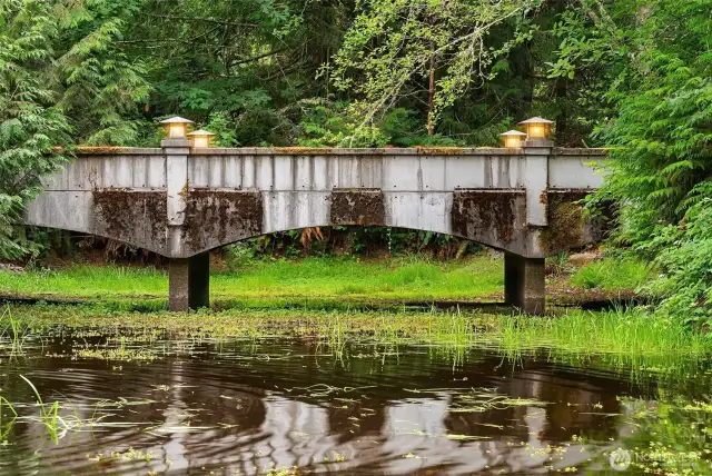 Upon entering the property, this solid moss covered cement bridge leads across the pond to the main home