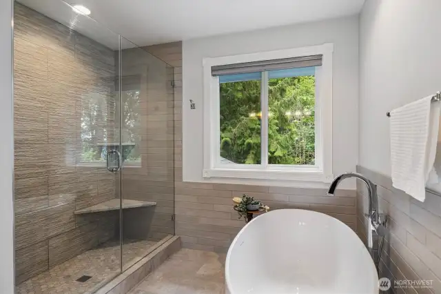 This primary bathroom features heated floors, tiled shower to the ceiling, large tub and adjoining walk-in closet