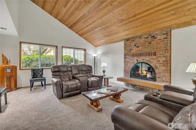 Living room with soaring cedar ceilings and wood burning fireplace.