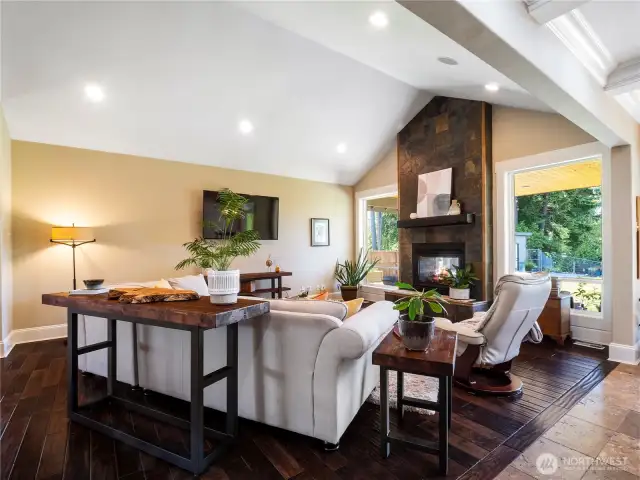 The living room area features beautiful wood floors, vaulted ceilings and a grand slate, indoor/outdoor gas fireplace.