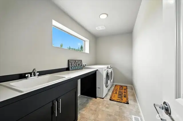 The generous upstairs laundry room includes built-in cabinetry, a deep sink, and is ideally situated just steps from the bedrooms for ultimate convenience.