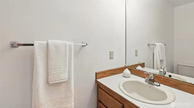 This bright & functional powder room featuring a large mirror, classic vanity, and neutral finishes is perfect for guests or daily convenience.