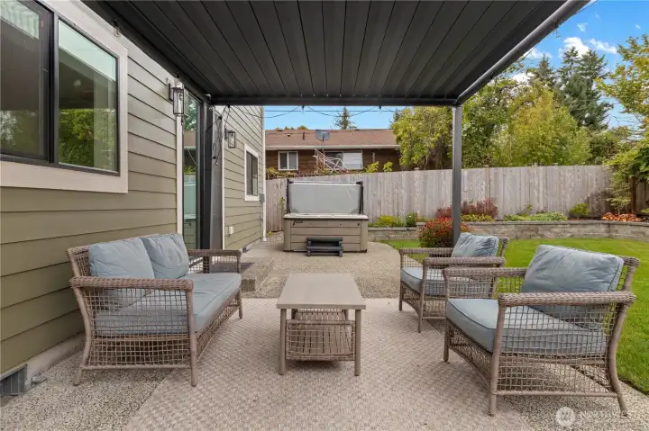 Great patio space out back with covered seating area and hot tub. Bonus - the louvers on the cover can open up when it's sunny.