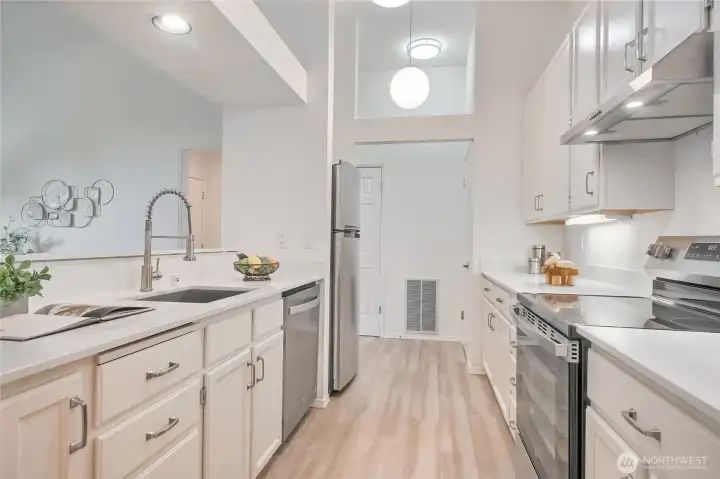All new appliances in this galley kitchen with granite countertops and new hardware.