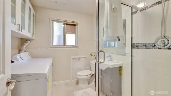 Spacious downstairs laundry room with extra cabinet storage, utility sink, and convenient shower.