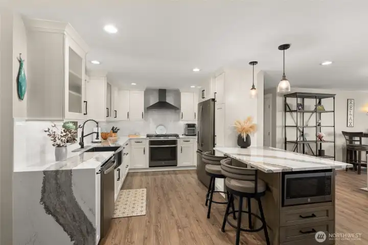 Functional galley kitchen w/ waterfall and slabs of quartz.