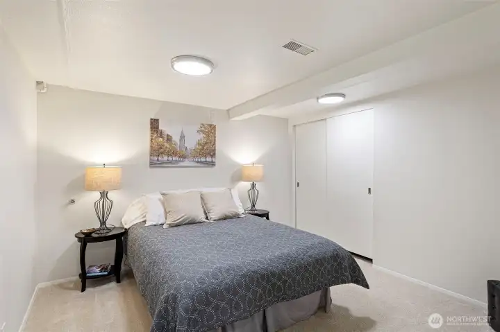 A generously sized lower-level bedroom with new carpet and updated lighting; non-conforming due to the absence of a window.