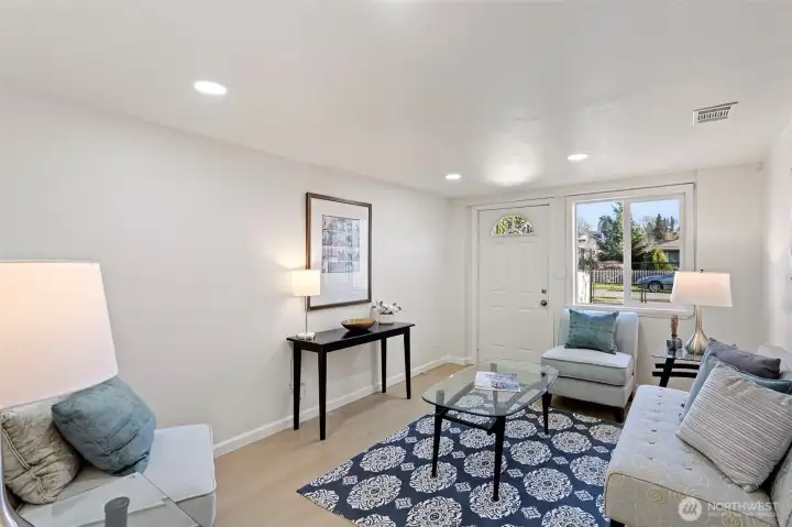 A comfortable lower-level family room with new LVP flooring, recessed lighting, and a flexible layout well suited for lounging, media, guests, or play, with direct exterior access to the front driveway.