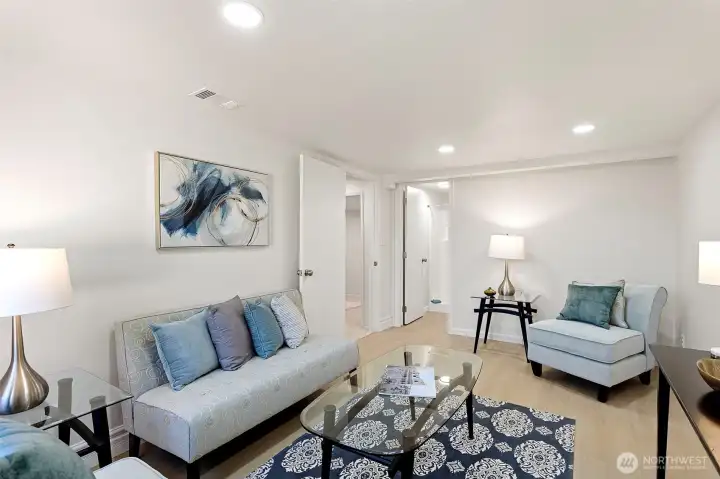 This family room connects directly to the adjacent ¾ bath and laundry area, with new LVP flooring adding durability and ease to the lower level.