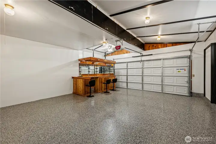 Garage with 220V, featuring a custom cedar bar with seating, new garage door & stylish flooring w/chip seal poly coating, easily convertible back to garage space if needed.