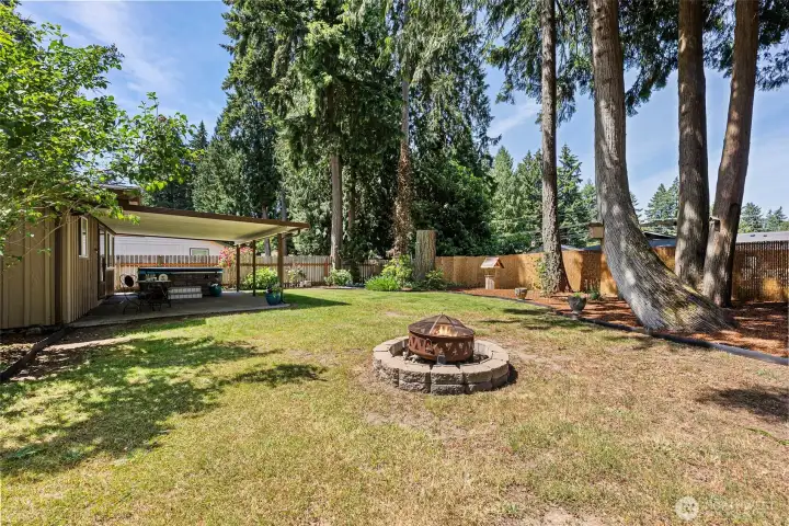 A spacious back yard features a cozy firepit perfect for gatherings