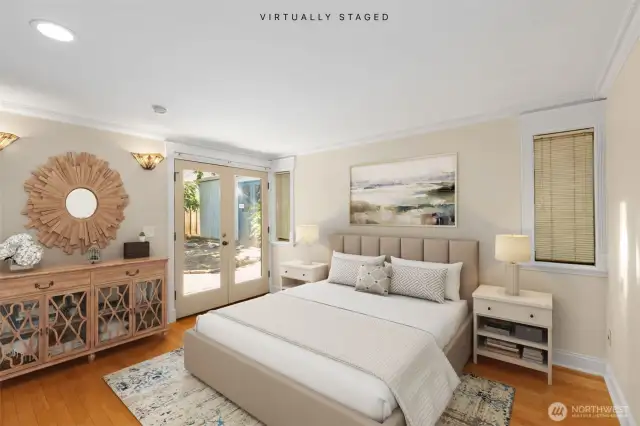 Primary bedroom with en-suite bath and French doors leading to the covered view patio. This image has been virtually staged.