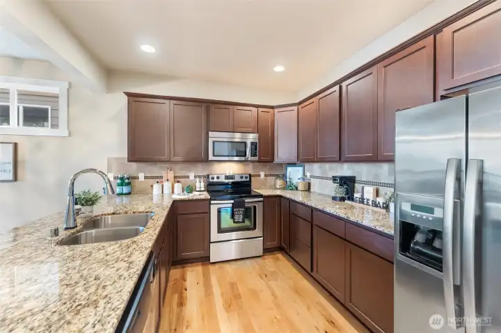 Chefs kitchen with SS appliances, granite countertops and full tile backsplash.