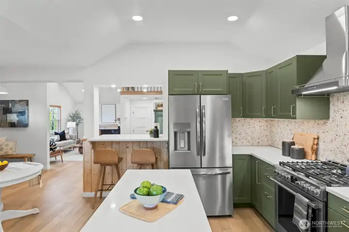 View of the gorgeous chef's kitchen looking into the living room. Backsplash was hand constructed with natural stone for a continuous one of a kind pattern