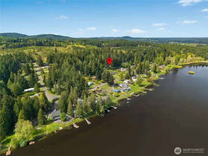 Aerial view shows the property location within a wooded lake community near the water.