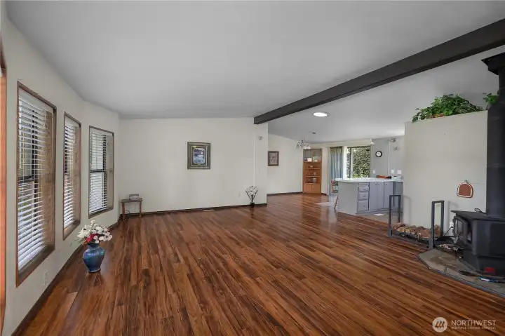 Gather in the spacious great room with warm wood-style flooring, large windows, and cozy woodstove.