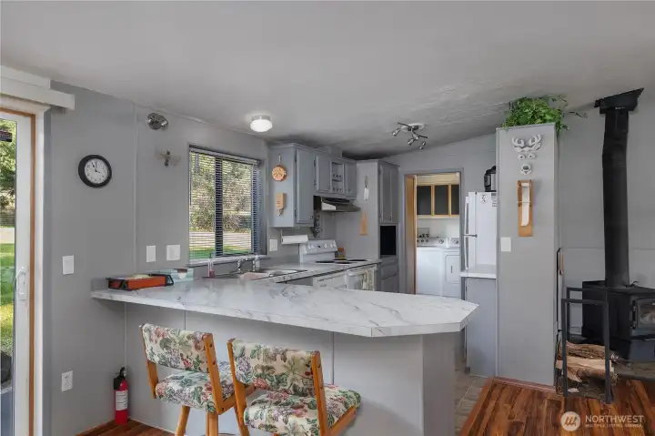 Kitchen features gray cabinetry, breakfast bar seating, and an open connection to the living area.
